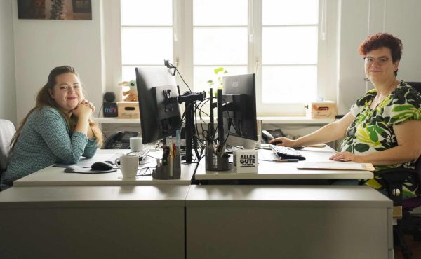 2 Frauen sitzen am Schreibtisch