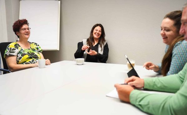 3 Frauen und ein Mann sitzen zusammen am Tisch und lachen